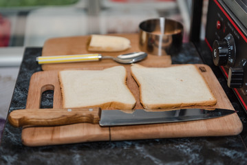 A slice of bread is on the table. Slice the bread. Cook your breakfast.
