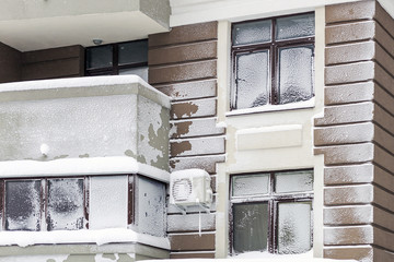 Wall with windows of modern high-rise apartment building covered with snow and frost after heavy windy snowstorm Snowfall and blizzard aftermath in winter. Cold snowy weather forecast