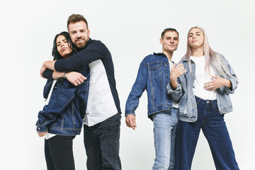 Fototapeta premium Group of smiling friends in fashionable jeans. The young men and woman posing at studio. The fashion, people, happy, lifestyle, clothes concept