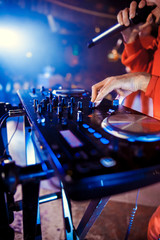 Dj mixes the track in the nightclub at party. In the background laser light show
