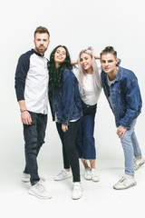 Fototapeta premium Group of smiling friends in fashionable jeans. The young men and woman posing at studio. The fashion, people, happy, lifestyle, clothes concept