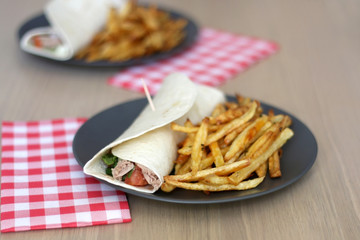 Tortilla wraps with tuna and various vegetables and french fries. Selective focus.