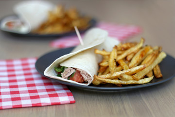 Tortilla wraps with tuna and various vegetables and french fries. Selective focus.
