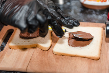 Smear chocolate paste on bread. Cooking a sweet sandwich. Nutritious breakfast.