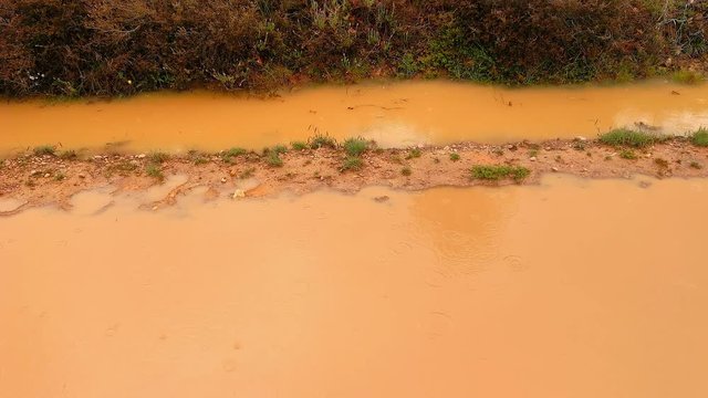 Gotas de lluvia salpicando en un charco de agua embarrada   en camino de tierra