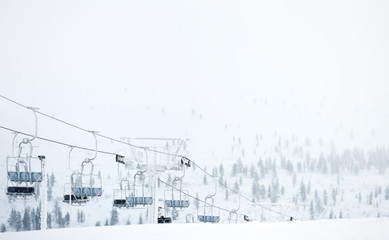 Ski lift in winter landscape. Snow covered forest trees in the background. Saariselkä, Lapland, Finland.