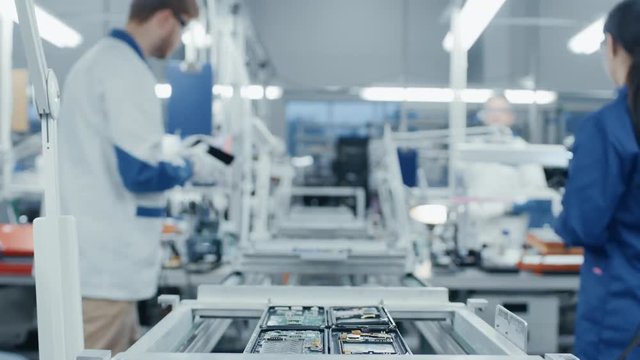 Time Lapse of Electronics Factory Workers Assembling Smartphone Circuit Boards by Hand While they Move on the Assembly Line. High Tech Factory Facility.