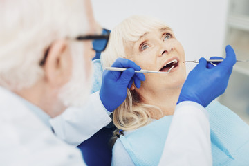 Attentive male dentist checking woman teeth
