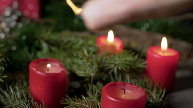 Night image of person lighting on candles on Christmas decoration.