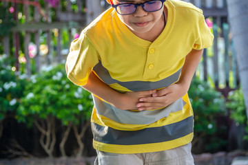 Naklejka premium Cute little boy suffering from stomach ache. Health and injury concept.