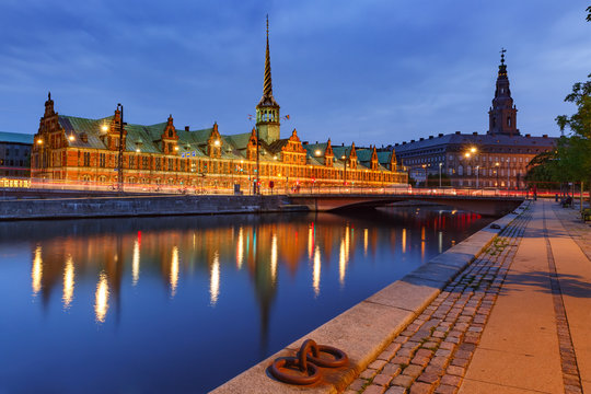 The Old Stock Exchange Boersen and Christiansborg Palace with their mirror reflection in canal at night, Copenhagen, capital of Denmark