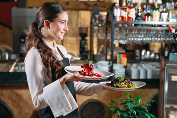 Waiter serving in motion on duty in restaurant. The waiter carries dishes