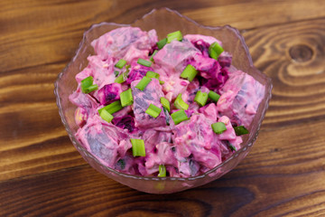 Tasty salad with herring, beetroot, eggs, onion and mayonnaise on wooden table
