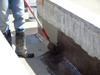 Waterproofing membrane applied by construction workers on top of concrete slab. Waterproofing layer to prevent water from entering below of the concrete slab. 