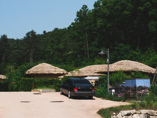 Fototapeta na wymiar Thatched houses and the modern car in the traditional asian village in South Korea