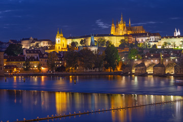 Fototapeta na wymiar Prague - The Charles Bridge, Castle and Cathedral from promenade over the Vltava river at dusk.