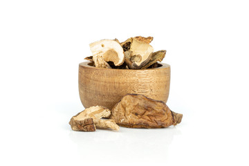 Lot of slices of edible dry brown mushroom boletus edulis variety with wooden bowl isolated on white background