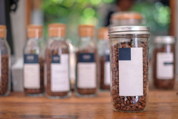 Coffee bean in glass bottle , coffee shop background 