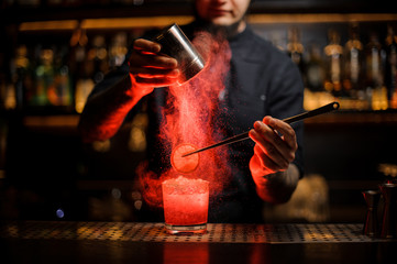 Fototapeta na wymiar Bartender adding spices powder into a cocktail glass with slice of lemon