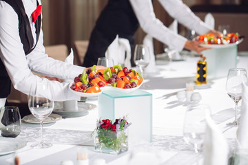 Waiters serving table in the restaurant preparing to receive guests.