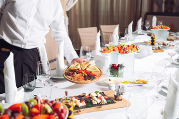 Waiter serving table in the restaurant preparing to receive guests.