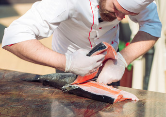 The chef cuts the salmon on the table.