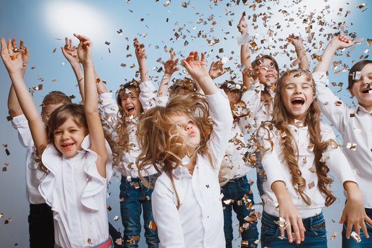 Adorable kids have fun together throw colourful confetti at birthday party. They playing together in different games, spending time in decorated studio. Children and events concept