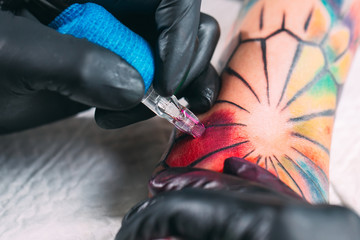 Professional tattoo artist makes a tattoo on a young girl's hand.