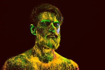 Concept. Portrait of a bearded man. The man is painted in ultraviolet powder.