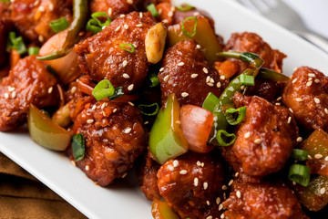 Indian Chilli Chicken dry, served in a plate over moody background. Selective focus