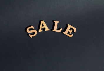 Yellow wooden letters on black background Sale.
