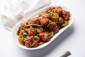 Indian Chilli Chicken dry, served in a plate over moody background. Selective focus