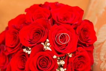 2 wedding rings on a bouquet of red roses