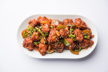 Indian Chilli Chicken dry, served in a plate over moody background. Selective focus