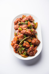 Indian Chilli Chicken dry, served in a plate over moody background. Selective focus