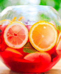 Summer cocktail. Fruit cocktail on green background. Citrus fruits, berries, strawberries, blueberries, mint, ice.