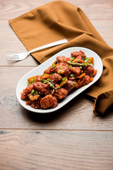 Indian Chilli Chicken dry, served in a plate over moody background. Selective focus