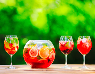 Summer cocktail. Fruit cocktail on green background. Citrus fruits, berries, strawberries, blueberries, mint, ice.