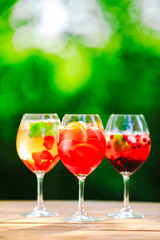 Summer cocktail. Fruit cocktail on green background. Citrus fruits, berries, strawberries, blueberries, mint, ice.