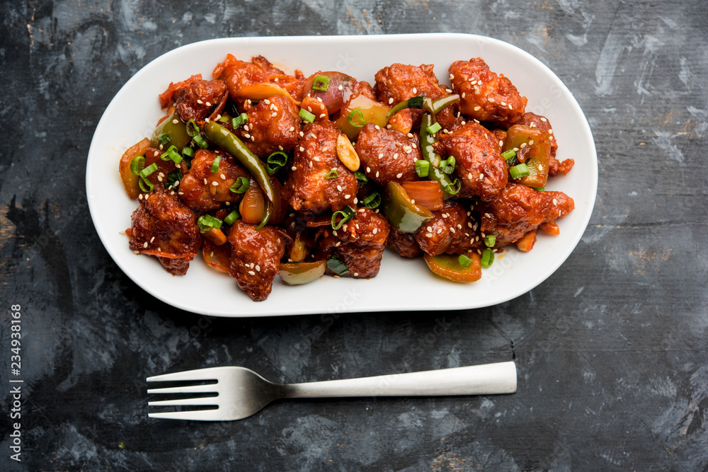 Wall mural Indian Chilli Chicken dry, served in a plate over moody background. Selective focus