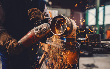 Close up of worker working with grinder. Workshop interior.