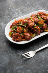 Indian Chilli Chicken dry, served in a plate over moody background. Selective focus