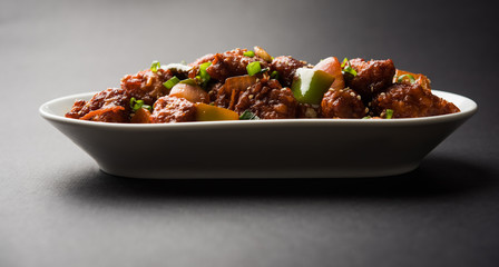 Indian Chilli Chicken dry, served in a plate over moody background. Selective focus