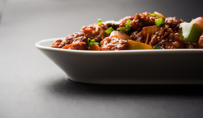 Indian Chilli Chicken dry, served in a plate over moody background. Selective focus