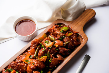 Indian Chilli Chicken dry, served in a plate over moody background. Selective focus