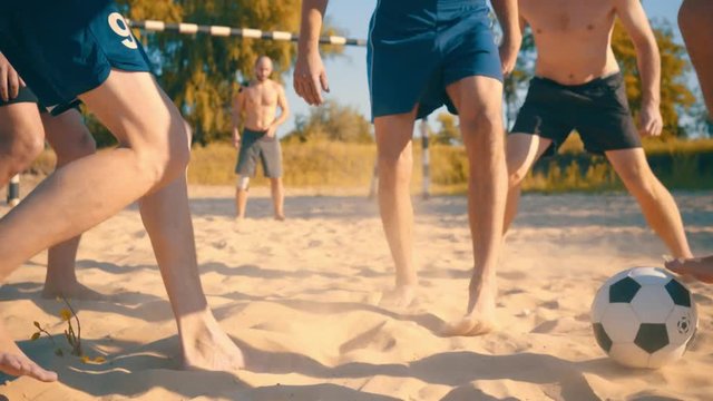 Soccer players in dynamic action funny play on the sand in beach football in summer sunny day under sunlight.

