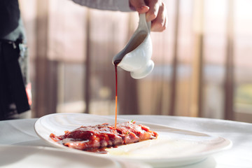 The Dish Is Carpaccio. The waiter pours the sauce over the dish Carpaccio.
