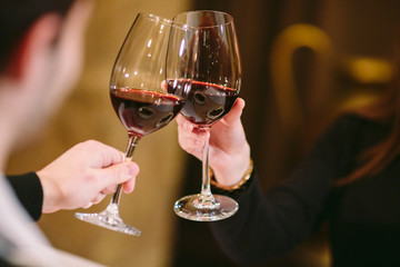Man and woman drinking red wine. In the picture, close-up hands with glasses.