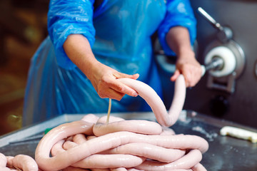 Butchers processing sausages at meat factory.