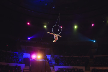 Aerial acrobat in the ring. A young girl performs the acrobatic elements in the air ring.